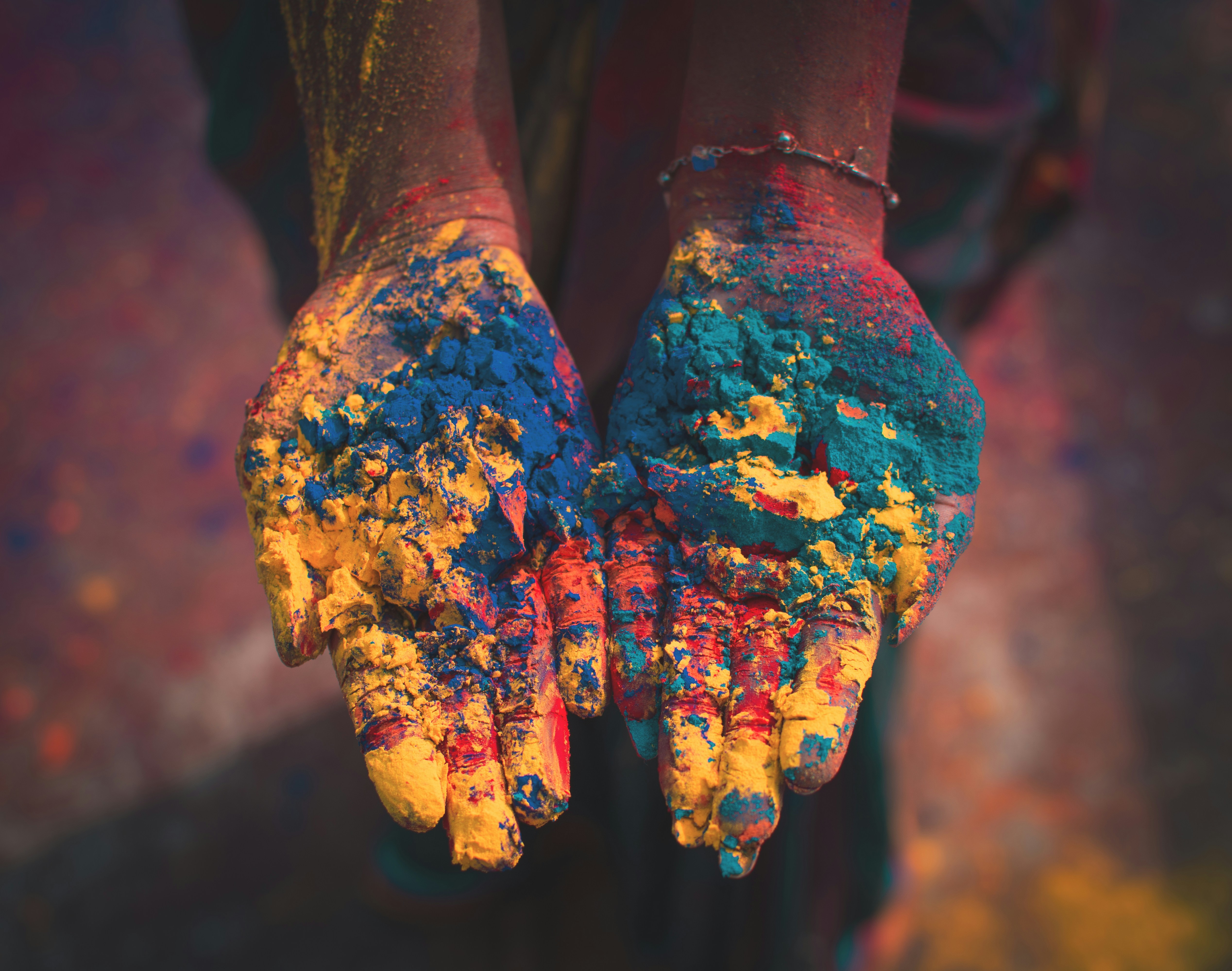 A pair of cupped hands covered in brightly coloured Holi powder, celebrating cultural tradition